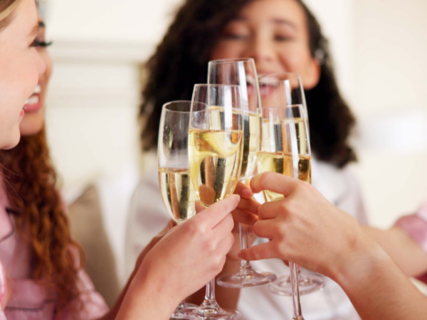 Friends clinking champagne glasses in a celebratory toast, smiling and enjoying a festive moment together.