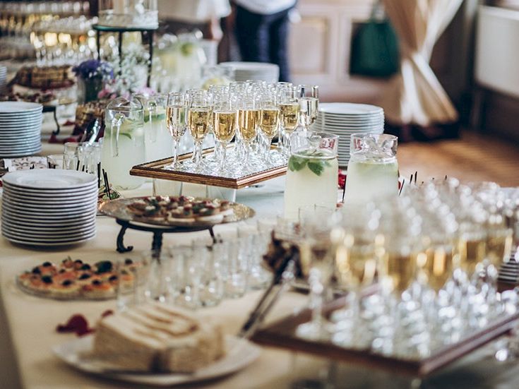 A lavish buffet setup with assorted pastries, desserts, and an array of champagne flutes and juice glasses on a long table.