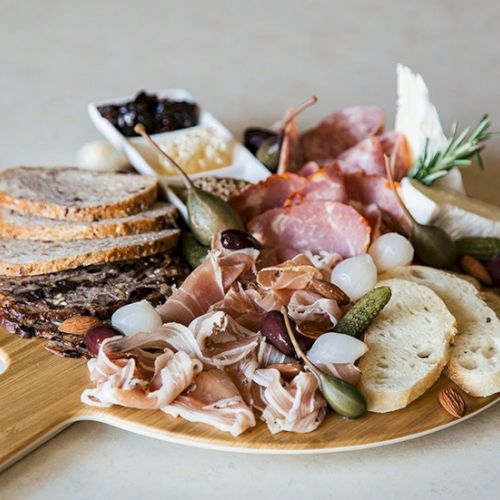 A plate of creamy mashed potatoes with shredded pork or brisket, pickled onions, herbs, and sauce, topped with greens, all on toast or bread.