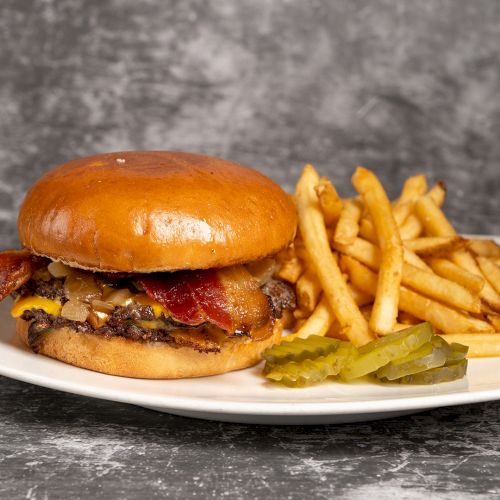 A hot dog on a bun with mustard and a side of curly fries, served on a plate with a dark background.